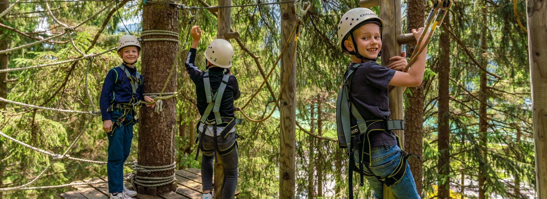 Drei Kinder klettern in einem Klettergarten.