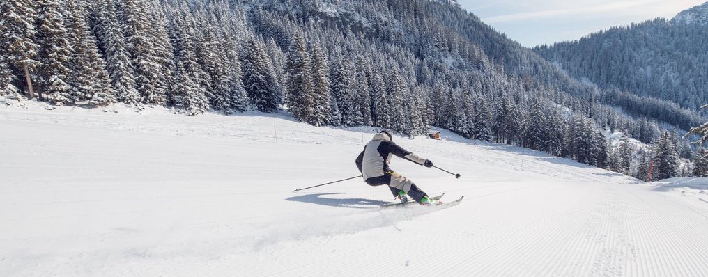 Ein Skifahrer fährt eine verschneite Piste hinunter.