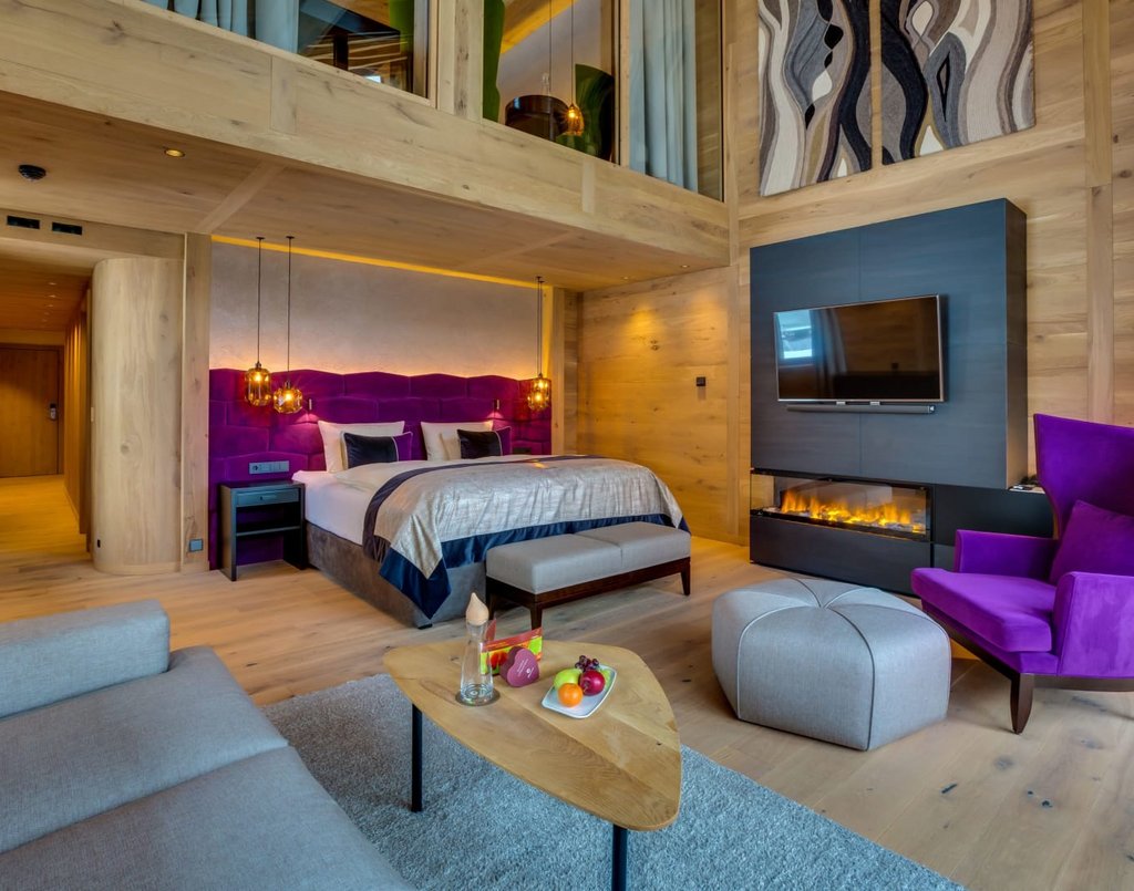 Suite mit großem Doppelbett, Fernseher und brennenden Kamin.