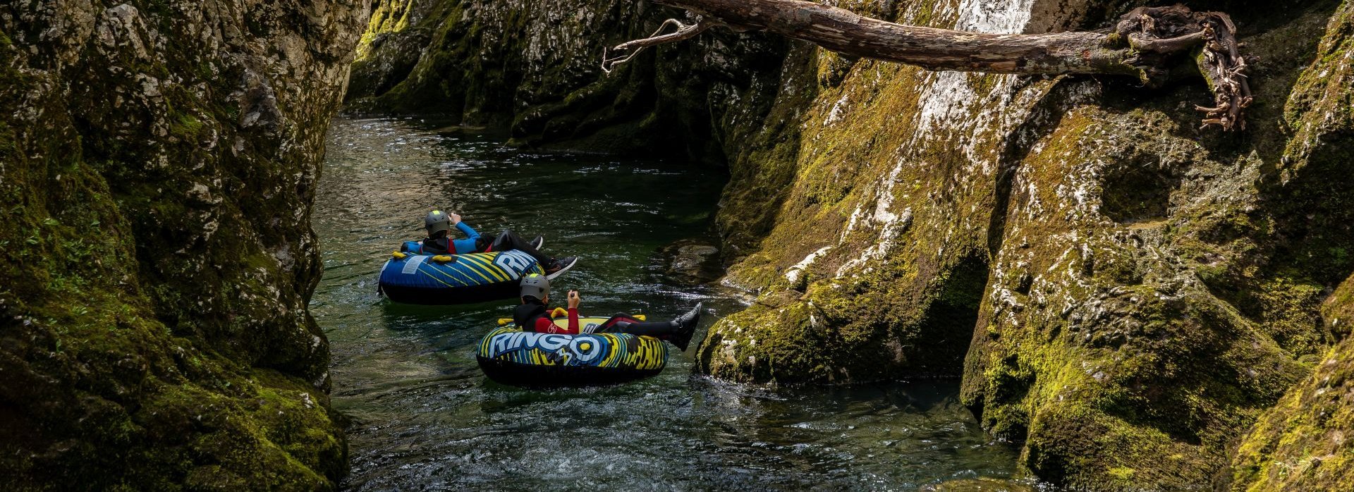 Mehrere Personen treiben auf aufblasbaren Reifen einen Fluss hinunter.