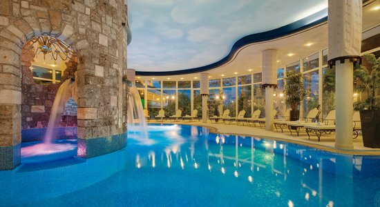 Neben einem großen Indoor Pool stehen mehrere Liegen.