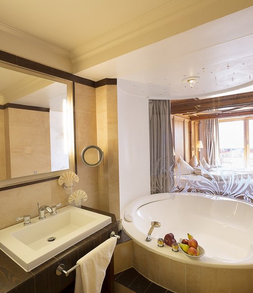 Ein Badezimmer mit großer Badewanne mit Blick auf das Schlafzimmer.