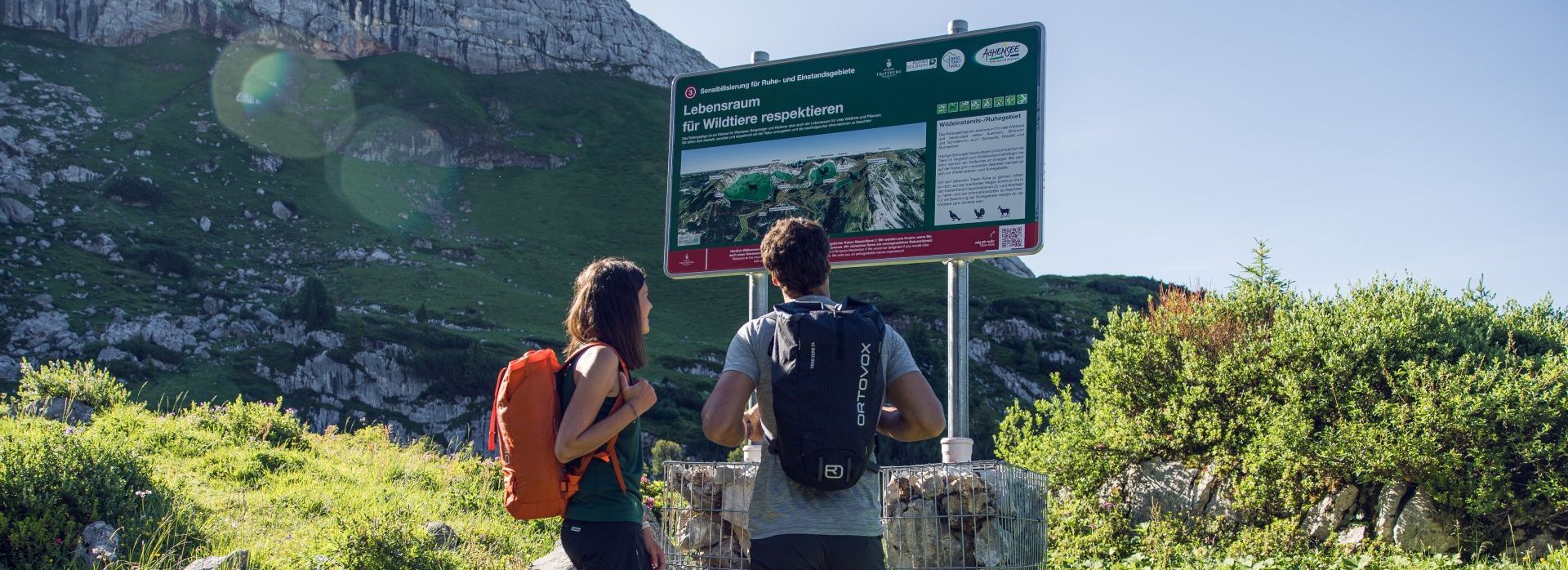 Ein Mann und eine Frau stehen vor einem Lehrpfad im Rofangebirge.