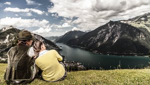 Ein Mann und eine Frau sitzen auf einer Wiese und blicken auf den Achensee.