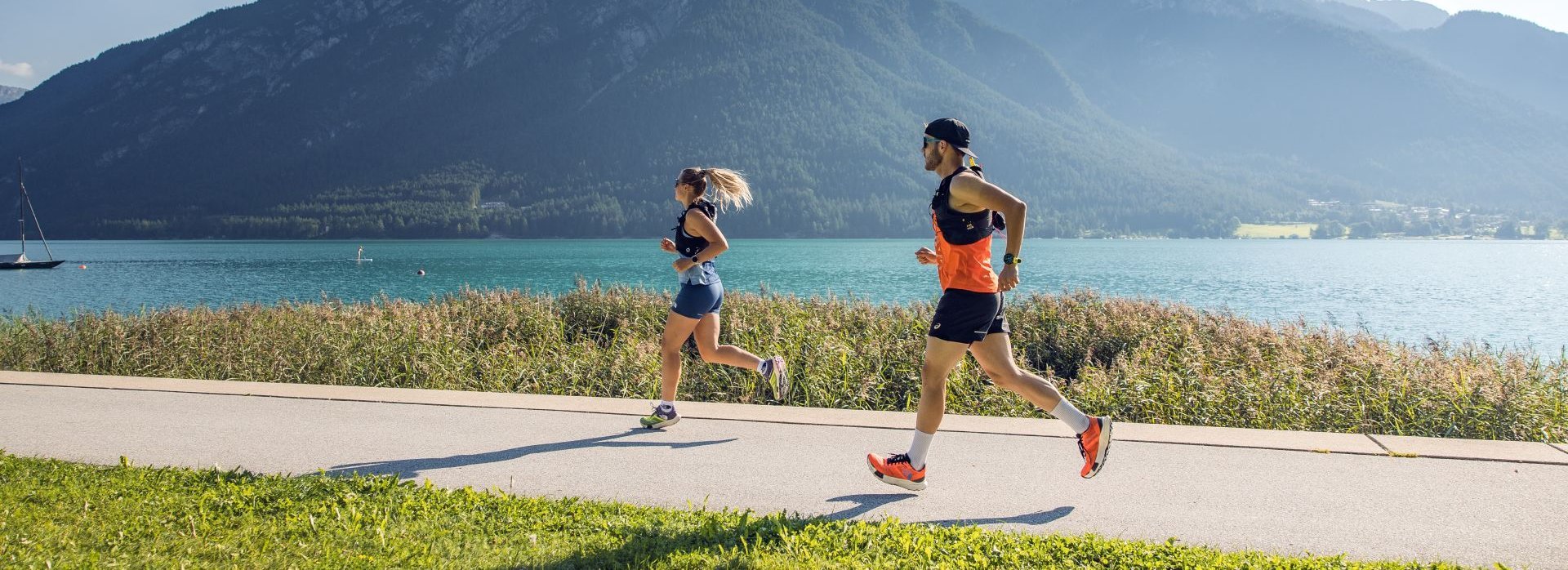 Zwei Personen joggen am Achensee entlang.