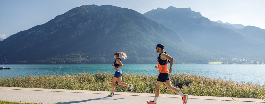 Zwei Personen joggen am Achensee entlang.