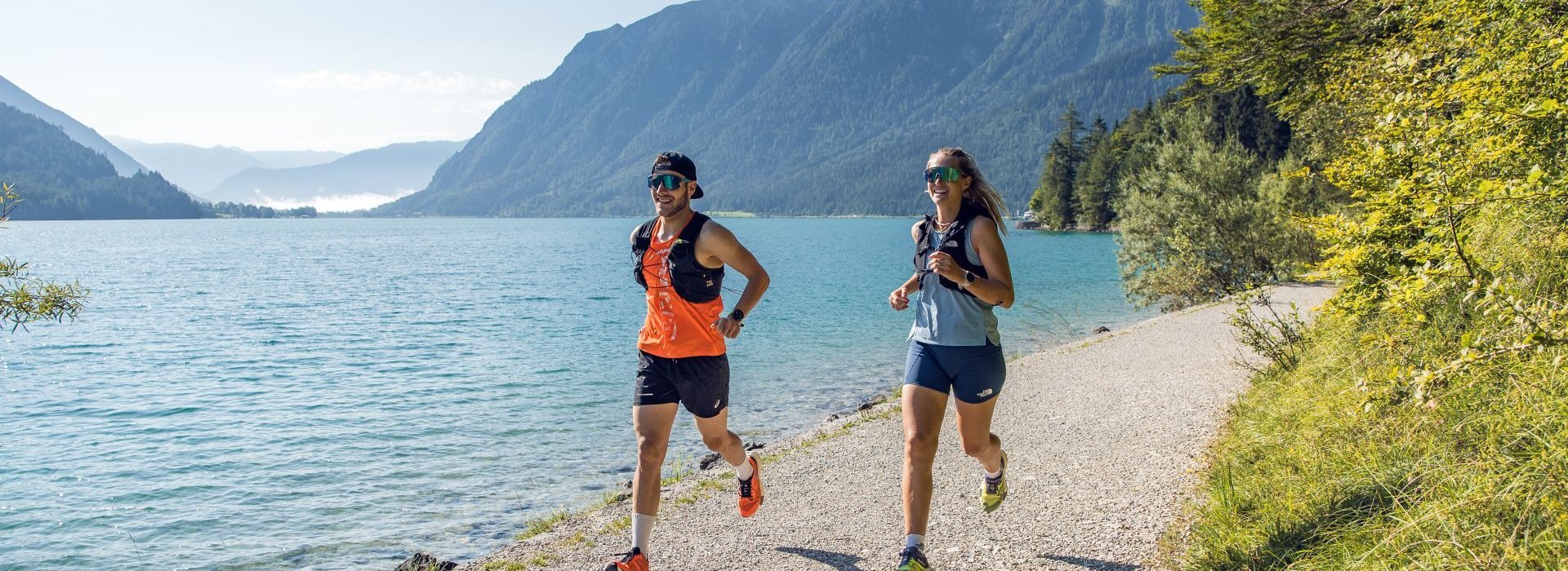 Ein Mann und eine Frau joggen am Ufer des Achensees entlang.