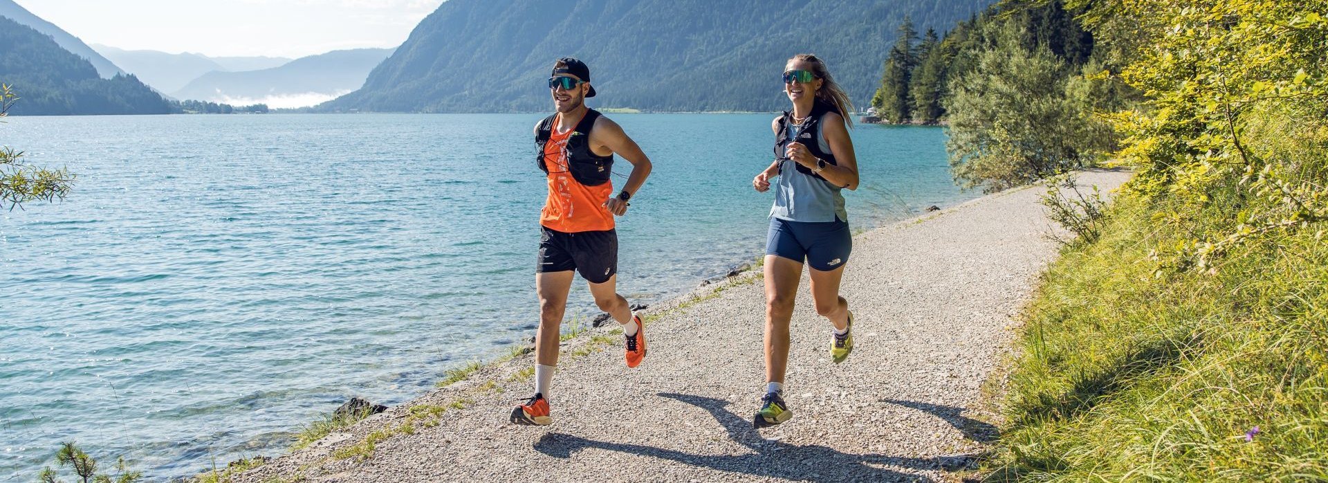 Ein Mann und eine Frau joggen am Ufer des Achensees entlang.